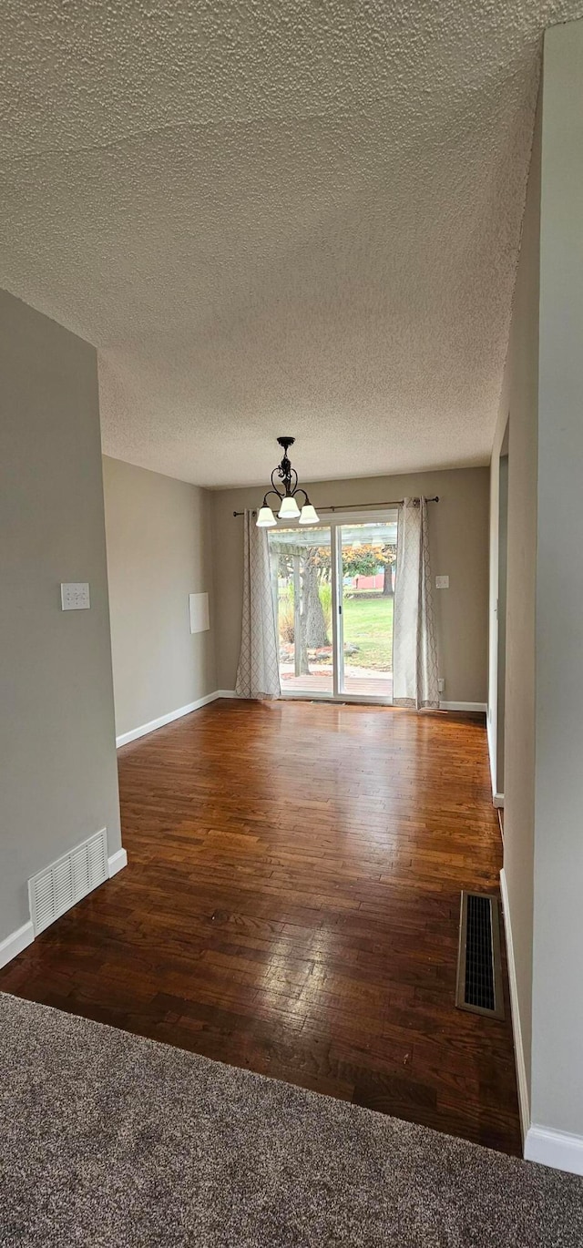 spare room featuring dark wood-type flooring and a textured ceiling