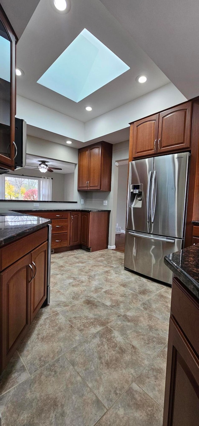 kitchen featuring ceiling fan, stainless steel refrigerator with ice dispenser, and a skylight