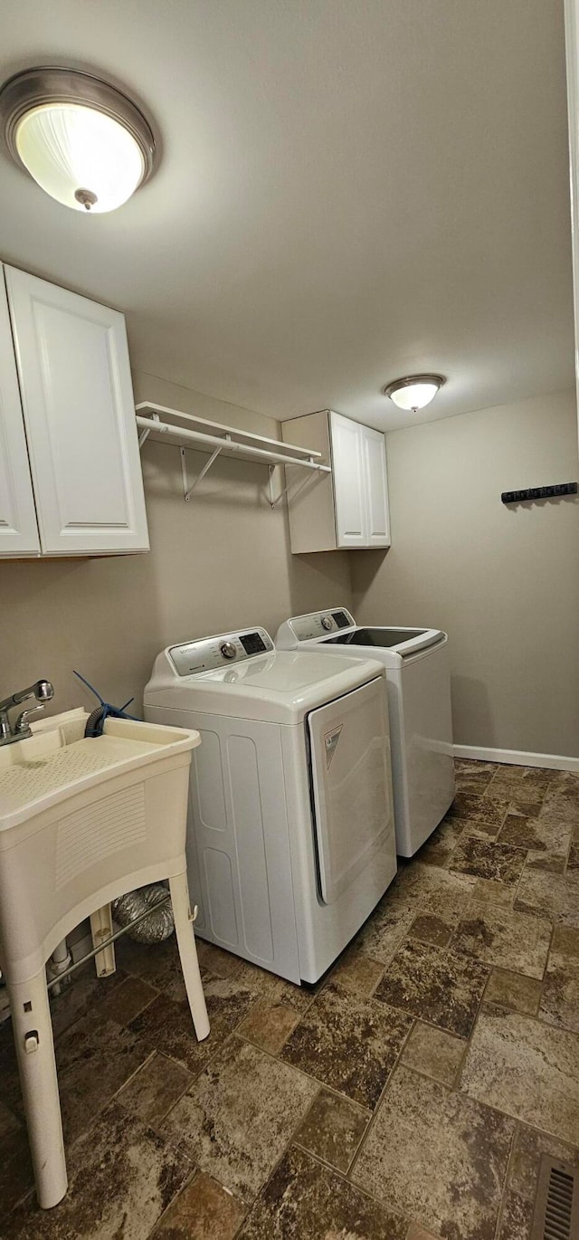 clothes washing area featuring cabinets and washer and clothes dryer