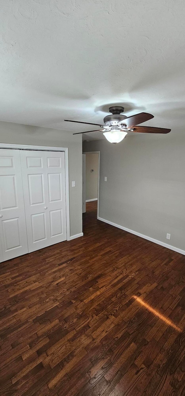 unfurnished bedroom featuring ceiling fan, dark hardwood / wood-style floors, a textured ceiling, and a closet