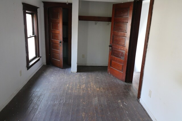 unfurnished bedroom featuring dark hardwood / wood-style floors and multiple windows