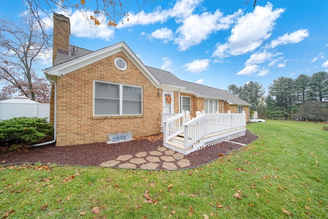 rear view of property with a wooden deck and a yard