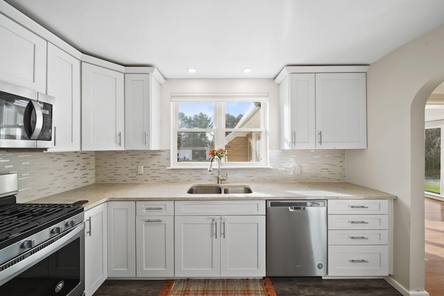 kitchen featuring white cabinets, appliances with stainless steel finishes, decorative backsplash, and sink