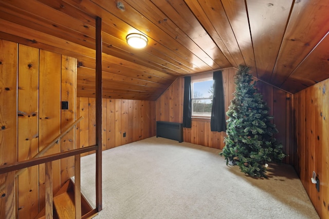 additional living space with radiator, wooden ceiling, vaulted ceiling, wooden walls, and carpet