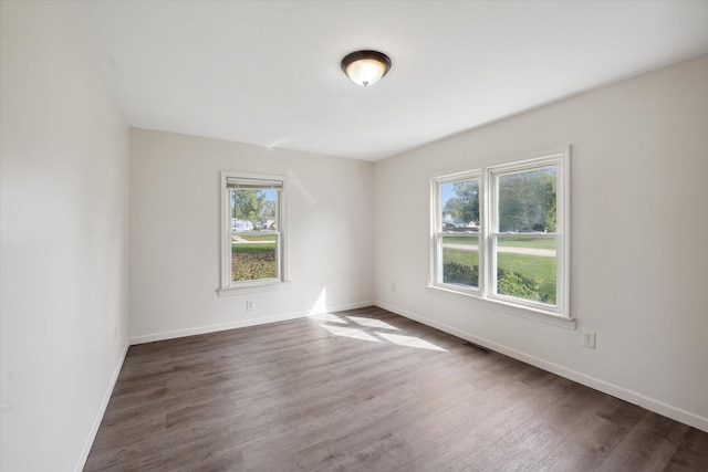 spare room featuring a wealth of natural light and dark hardwood / wood-style floors