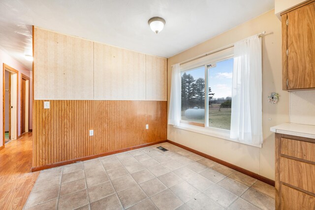 unfurnished room featuring wooden walls and light hardwood / wood-style flooring