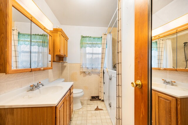 bathroom with a shower with curtain, vanity, toilet, and tile walls