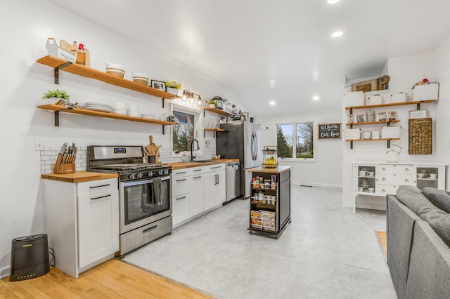 kitchen with sink, light hardwood / wood-style flooring, appliances with stainless steel finishes, butcher block countertops, and white cabinetry