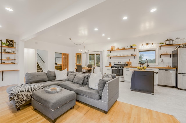 living room featuring an inviting chandelier, light hardwood / wood-style flooring, and sink