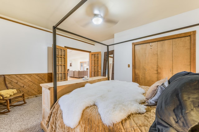 bedroom with ceiling fan, wood walls, and light colored carpet