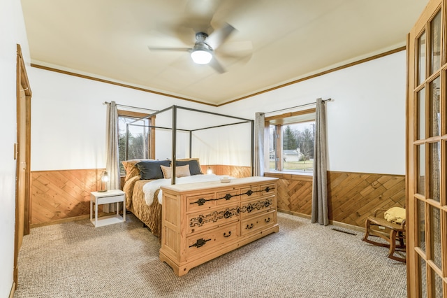 carpeted bedroom featuring ceiling fan, wood walls, and ornamental molding