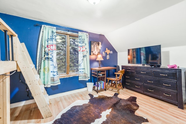 bedroom with hardwood / wood-style floors and lofted ceiling