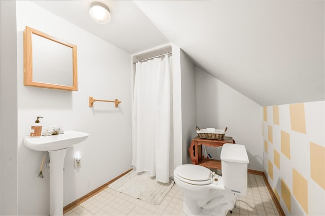 bathroom with toilet, lofted ceiling, and sink