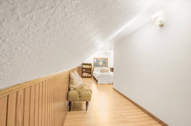 interior space with hardwood / wood-style flooring, lofted ceiling, a textured ceiling, and wooden walls