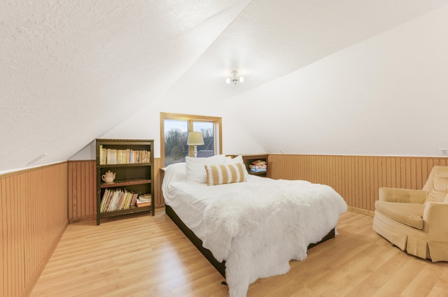 bedroom featuring wooden walls, wood-type flooring, and a textured ceiling