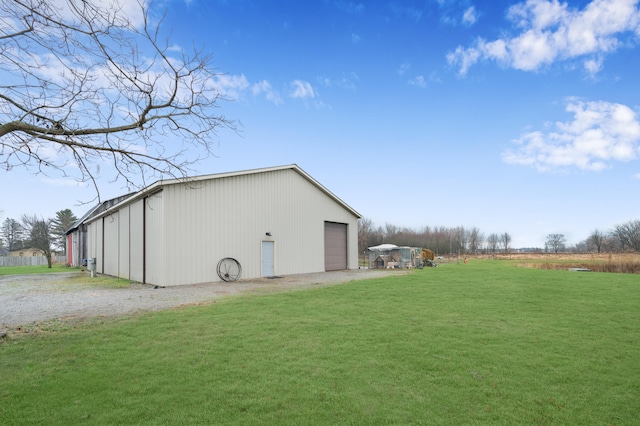 exterior space featuring a lawn, a garage, and an outbuilding