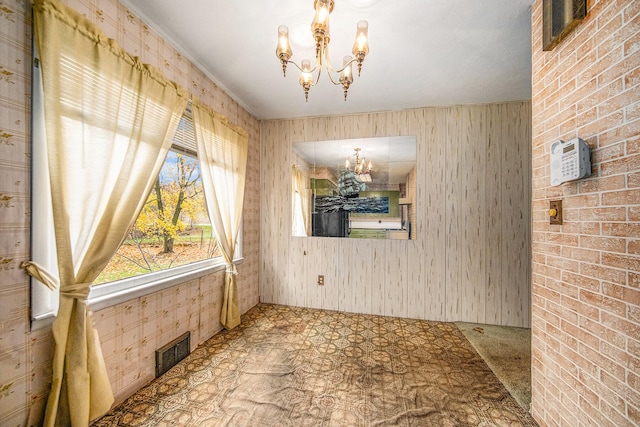 unfurnished dining area featuring wooden walls, a notable chandelier, and brick wall