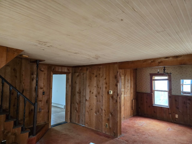 carpeted empty room with wooden walls and a baseboard heating unit