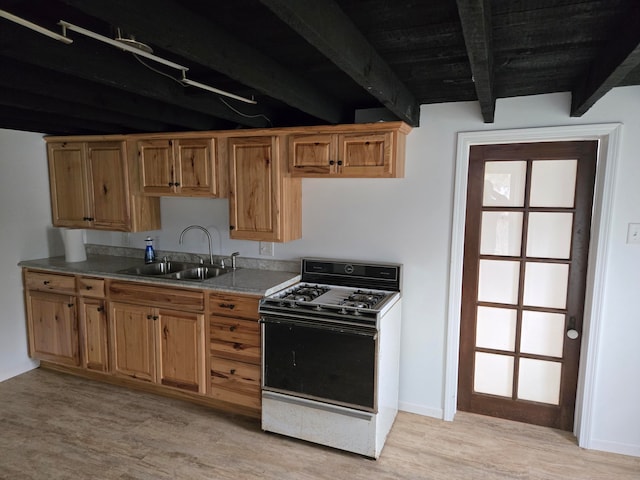 kitchen with beamed ceiling, light hardwood / wood-style floors, white gas range, and sink