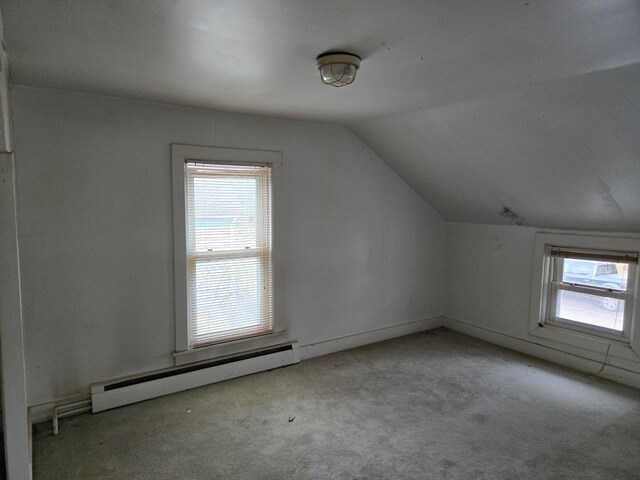 additional living space featuring light carpet, a baseboard radiator, and vaulted ceiling