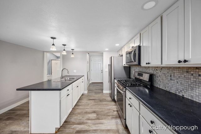 kitchen featuring white cabinetry, sink, light hardwood / wood-style floors, decorative light fixtures, and appliances with stainless steel finishes