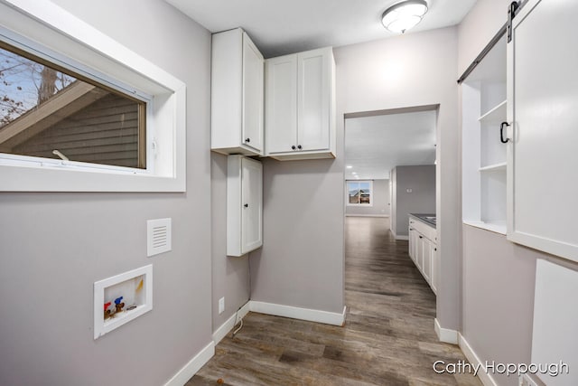 laundry room featuring cabinets, washer hookup, a barn door, and dark hardwood / wood-style flooring