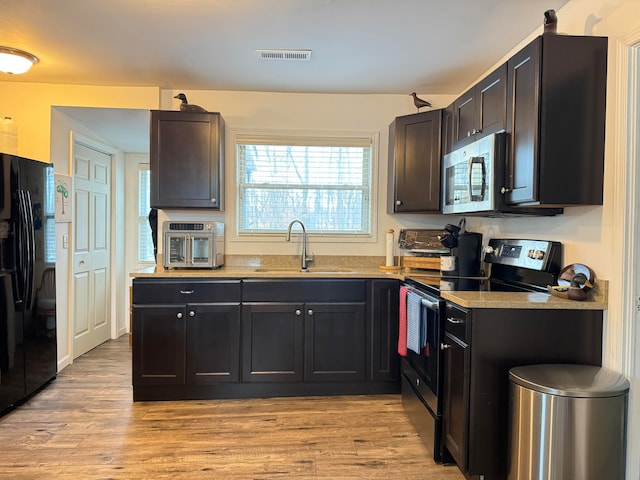 kitchen with light hardwood / wood-style floors, sink, and appliances with stainless steel finishes