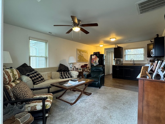 living room featuring ceiling fan, wood-type flooring, and sink