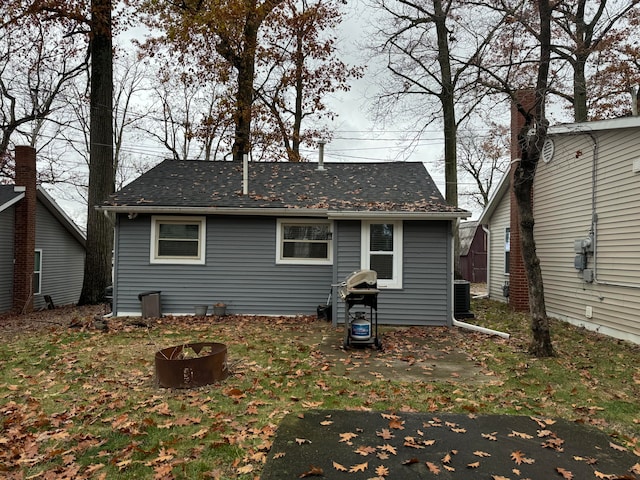 back of house featuring an outdoor fire pit and central air condition unit