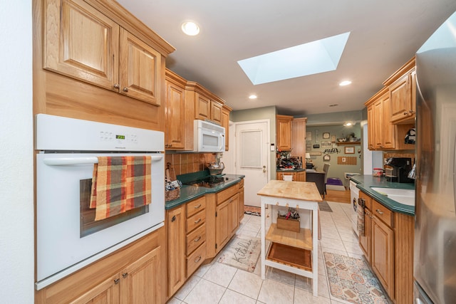 kitchen featuring decorative backsplash, a skylight, white appliances, butcher block counters, and light tile patterned flooring