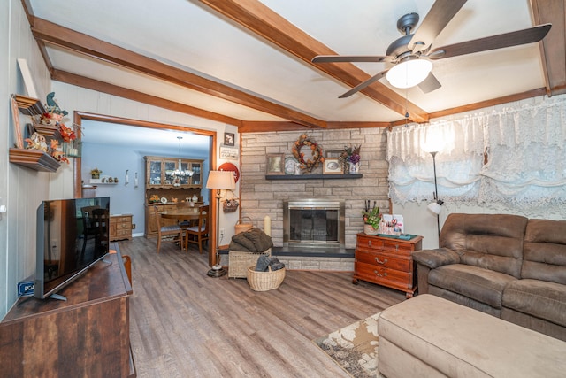 living room featuring a fireplace, beamed ceiling, ceiling fan with notable chandelier, and hardwood / wood-style flooring