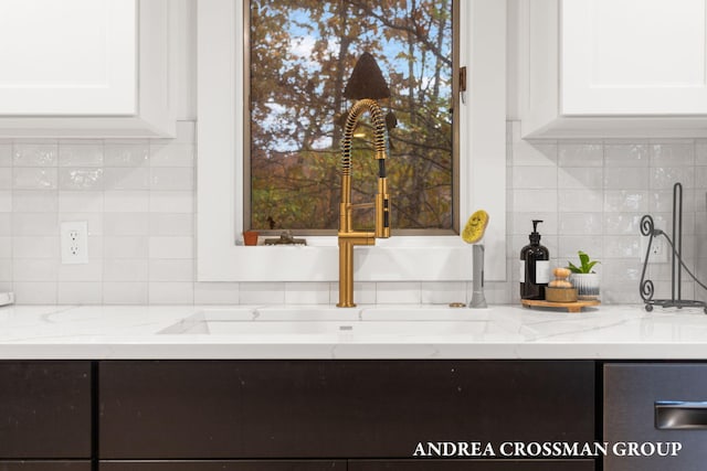 interior details with light stone countertops, decorative backsplash, and white cabinets