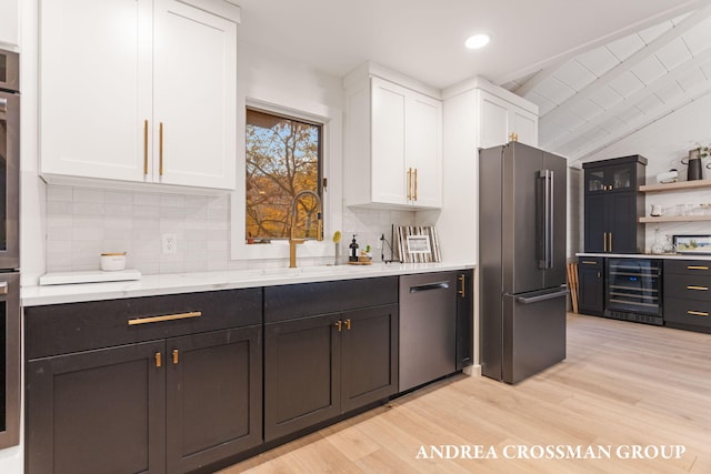 kitchen with stainless steel appliances, wine cooler, backsplash, white cabinets, and light wood-type flooring