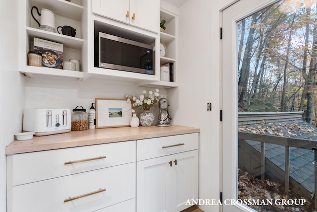 bar featuring white cabinets, butcher block countertops, and stainless steel microwave