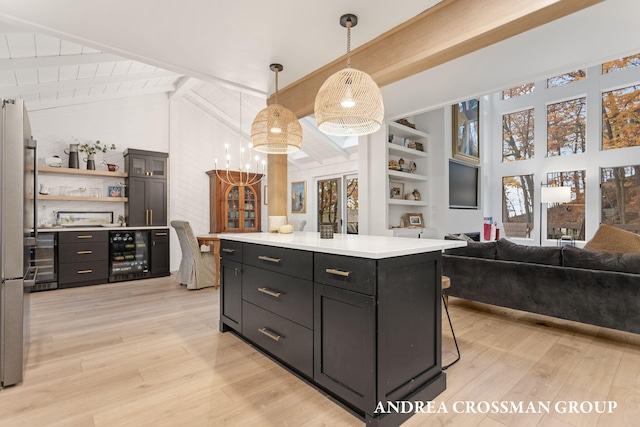 kitchen featuring hanging light fixtures, light hardwood / wood-style floors, a kitchen island, and beverage cooler