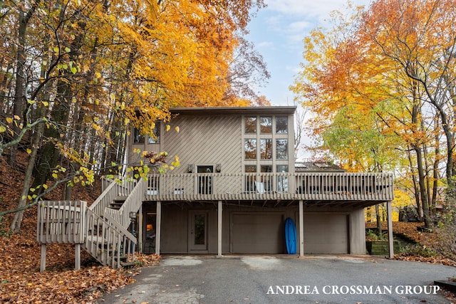 rear view of property with a wooden deck and a garage