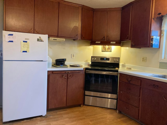 kitchen with stainless steel range, white fridge, and light hardwood / wood-style floors