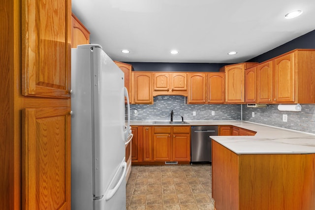 kitchen featuring decorative backsplash, sink, stainless steel dishwasher, and white refrigerator