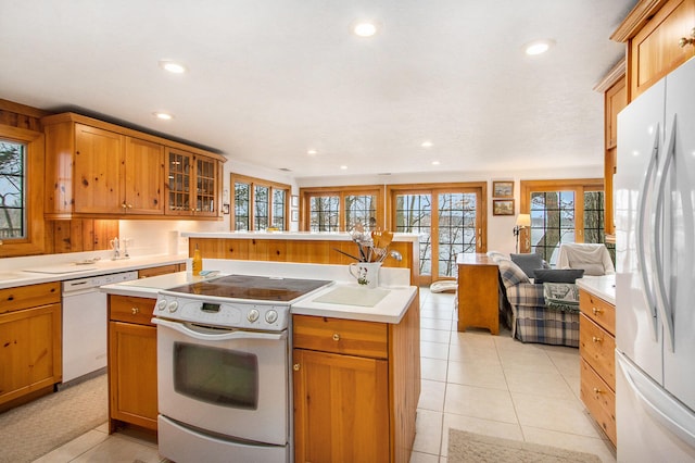 kitchen featuring a kitchen island with sink, light tile patterned floors, and white appliances