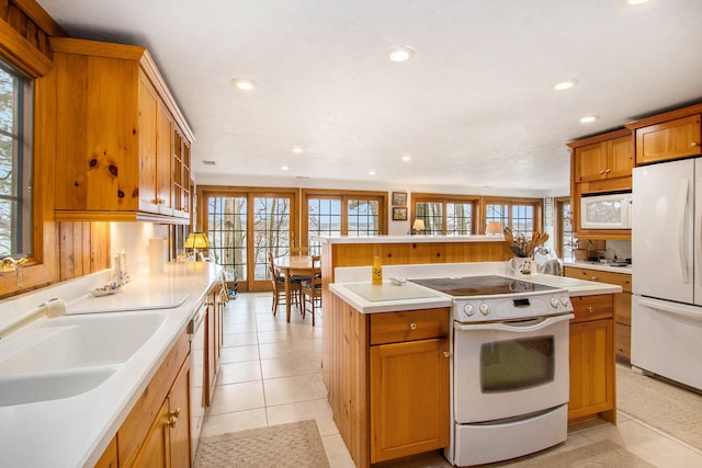 kitchen featuring sink, an island with sink, light tile patterned flooring, and white appliances