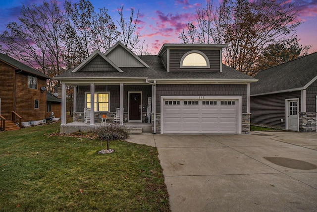 18481 N Fruitport Rd, Spring Lake, MI 49456 - view of front facade featuring driveway, a porch, a lawn, stone siding, and a garage