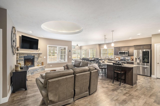 18481 N Fruitport Rd, Spring Lake, MI 49456 - living room featuring light wood-type flooring, a stone fireplace, baseboards, and recessed lighting