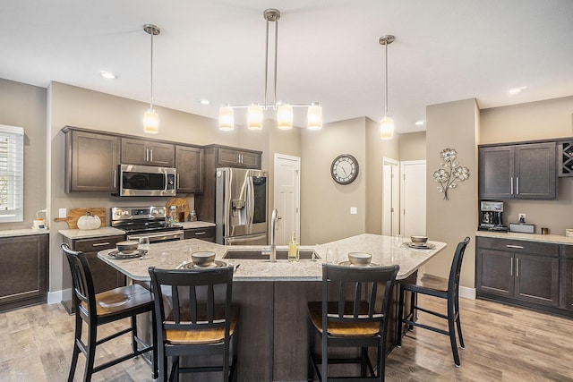 18481 N Fruitport Rd, Spring Lake, MI 49456 - kitchen with stainless steel appliances, a sink, dark brown cabinetry, a breakfast bar area, and a kitchen island with sink