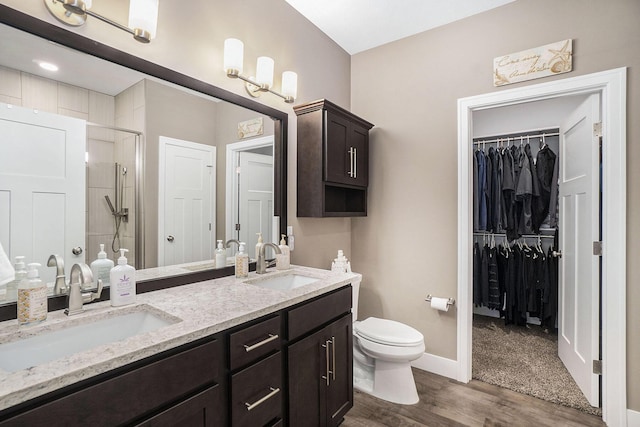 18481 N Fruitport Rd, Spring Lake, MI 49456 - bathroom featuring a shower stall, wood finished floors, double vanity, a spacious closet, and toilet