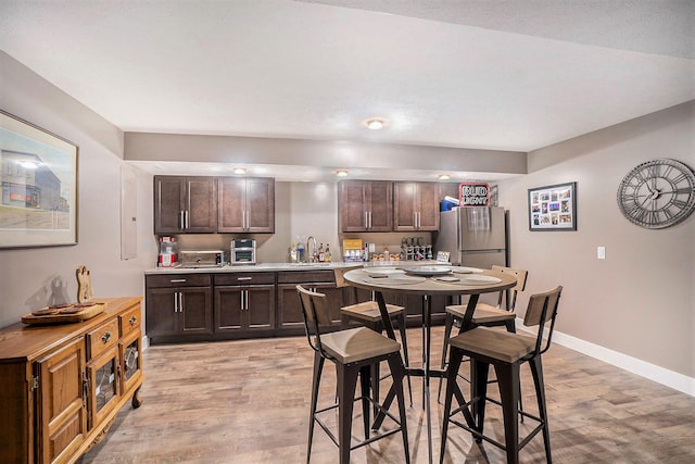 18481 N Fruitport Rd, Spring Lake, MI 49456 - kitchen featuring freestanding refrigerator, dark brown cabinetry, light wood-style flooring, light countertops, and baseboards