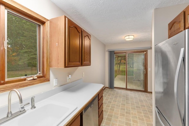 kitchen with a healthy amount of sunlight, a textured ceiling, and appliances with stainless steel finishes