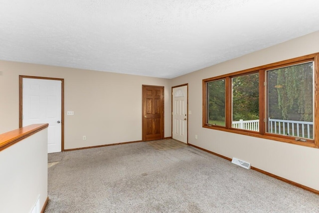 carpeted empty room featuring a textured ceiling