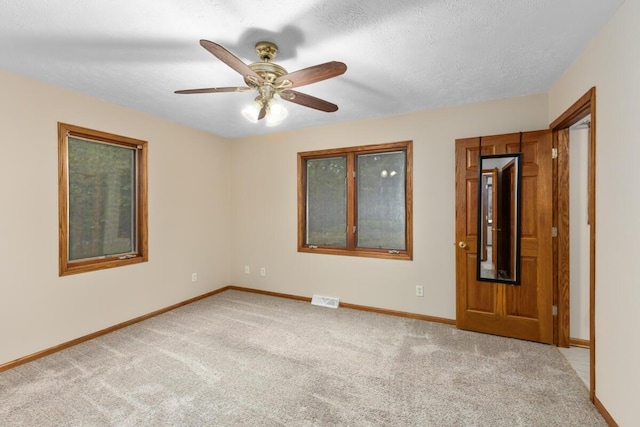 unfurnished room featuring light carpet, a textured ceiling, and ceiling fan