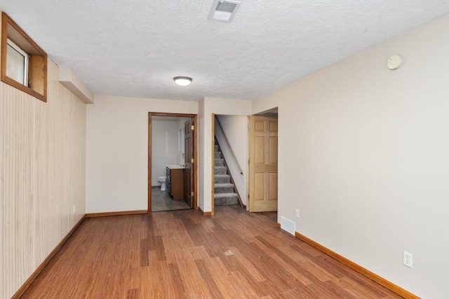 interior space with wood walls, a textured ceiling, and light hardwood / wood-style flooring