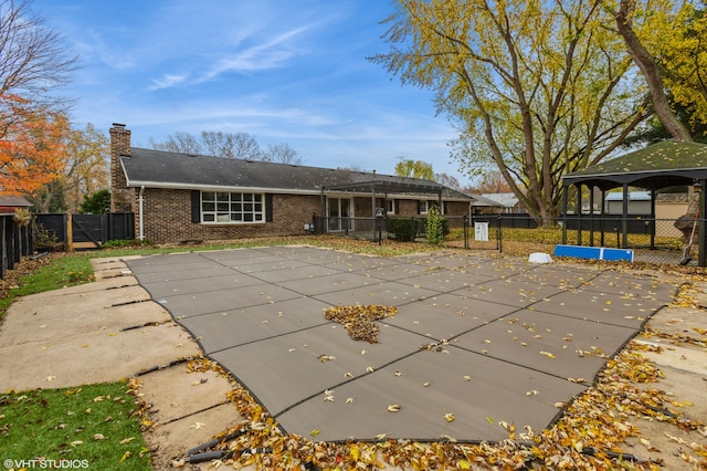 rear view of property with a covered pool